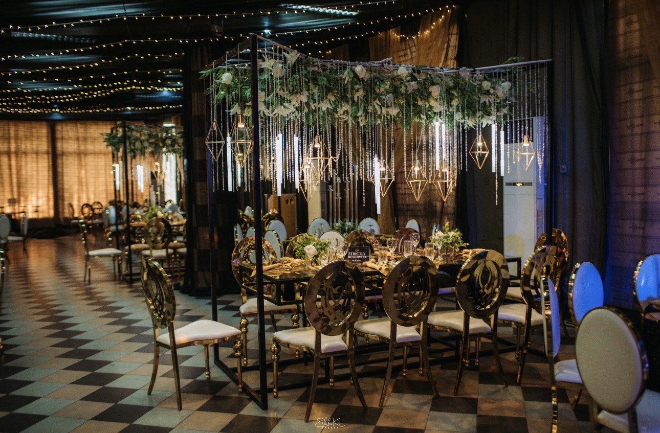 Outdoor reception with gold chairs on green carpet